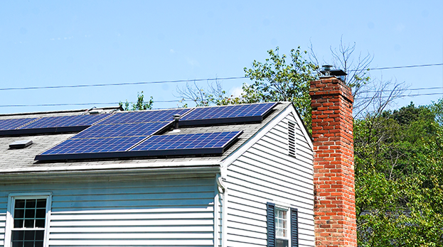 solar panels on top of a roof of residential home with chimney