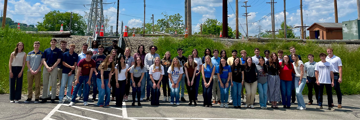30 DLC interns smiling for a photo in front of pole yard