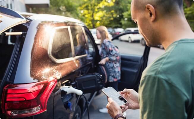 Person charging car while looking at phone