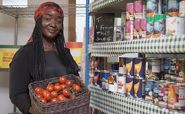 person at food pantry holding basket of tomatoes